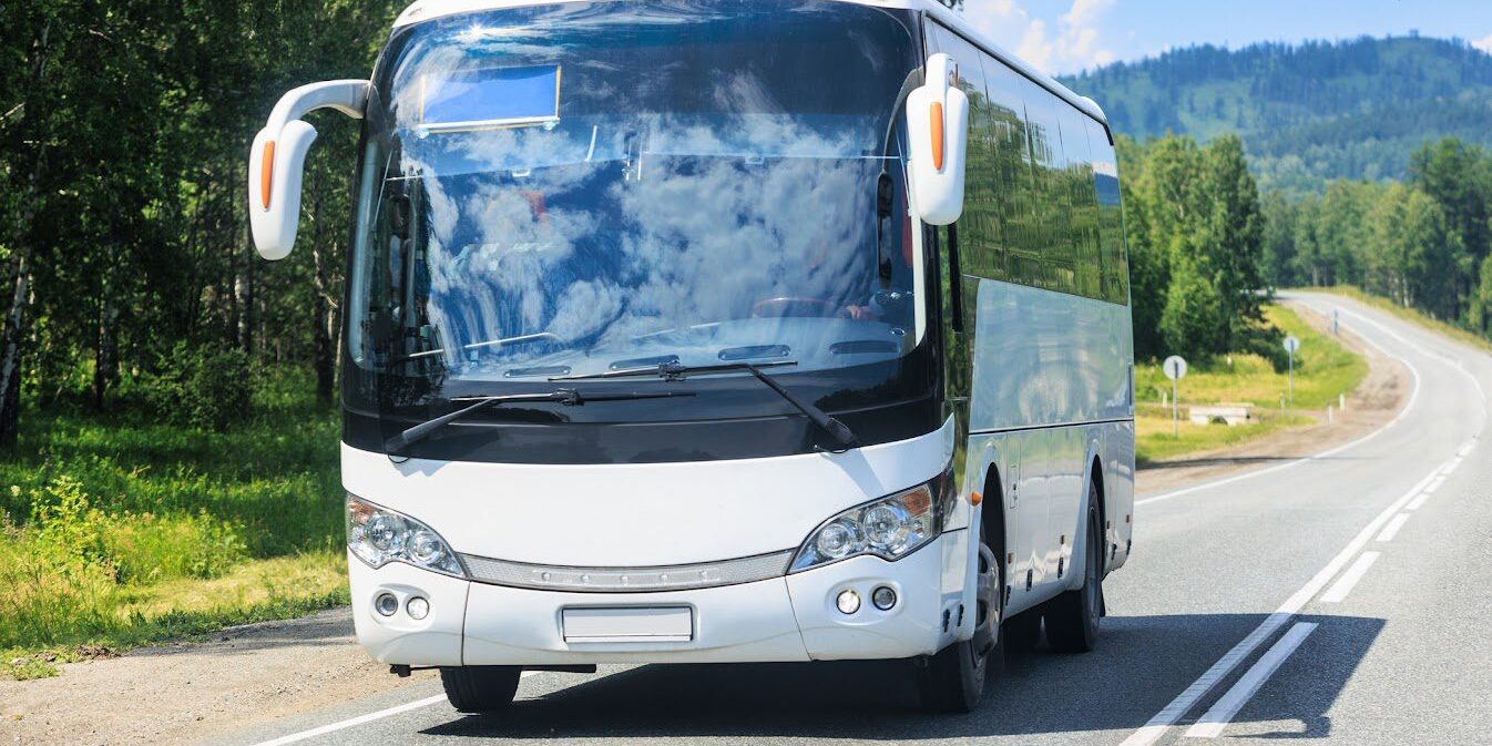 tourist bus moves along a country road on a sunny summer day